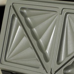 Smörgåsjärn i metall med trekantig mönstring för grillade smörgåsar.