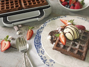 Chokladvåfflor med vaniljglass och jordgubbar serverade på tallrik.