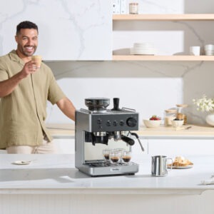 Man njuter av kaffe bredvid en modern espressomaskin i ett stilrent kök.